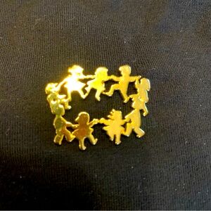 Gold-toned circle pin. Dancing children!